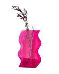 Eine pinke, transparente Vase mit einer rosa-farbenen Trockenblume